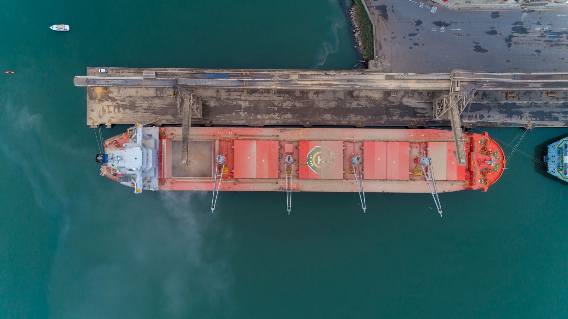 Vista aérea de um navio cargueiro atracado no porto de São Francisco do Sul, com a movimentação marítima ao redor.
