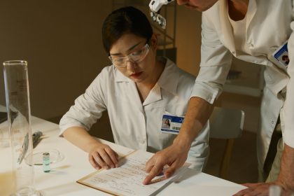 Dois pesquisadores de jaleco analisam anotações durante um estudo em um laboratório.